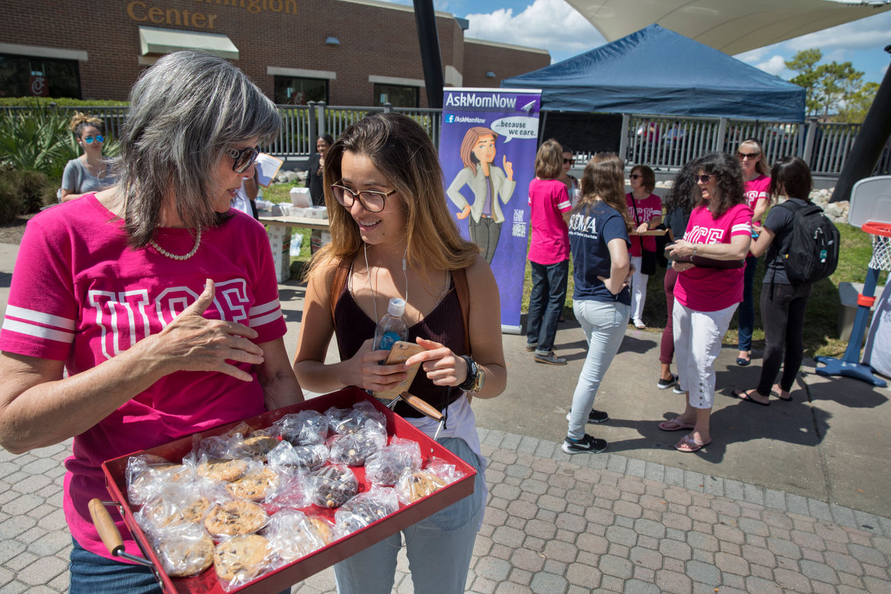 moms hand out cookies to college students