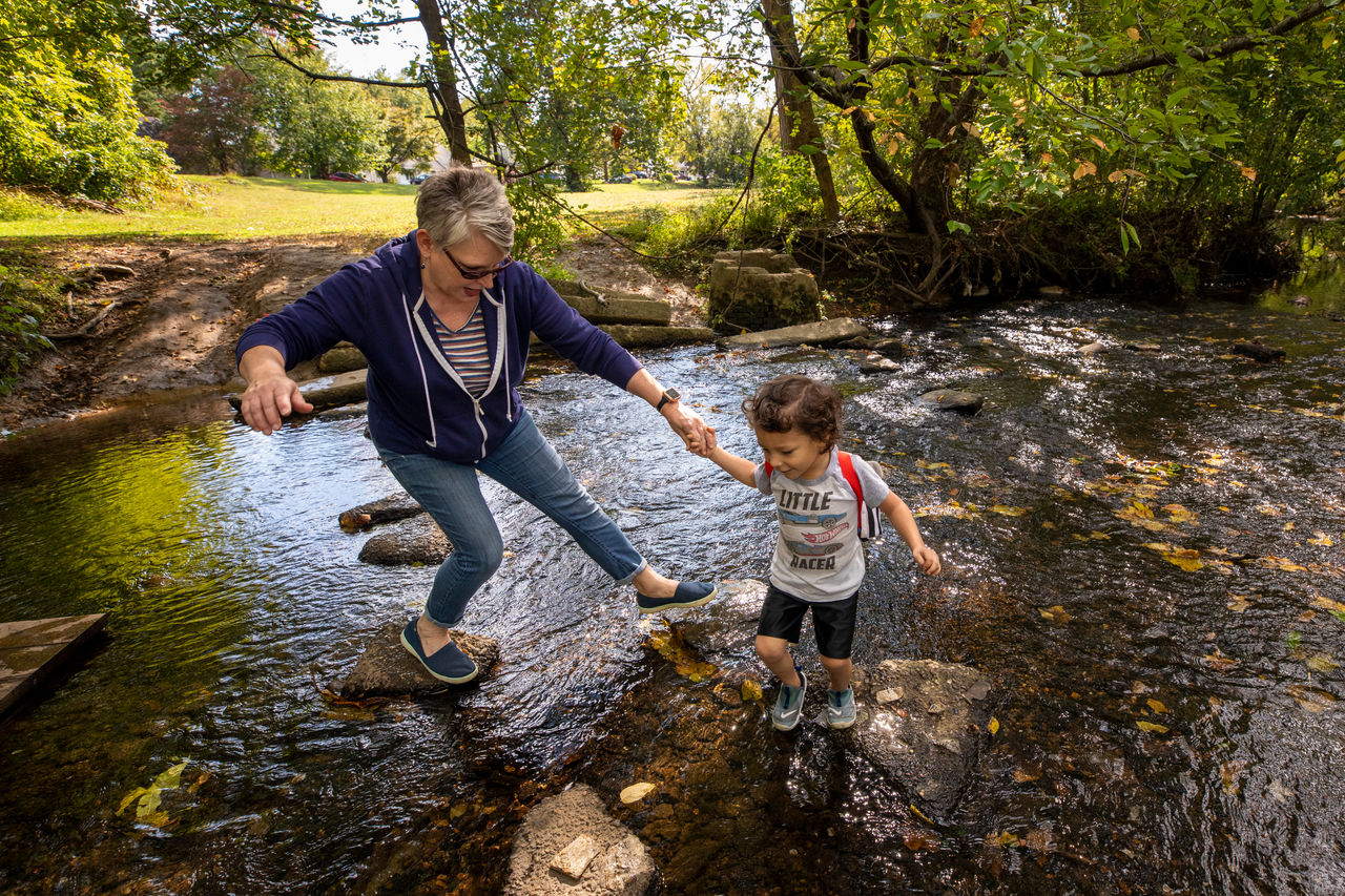 a little boy and old woman explore a creek