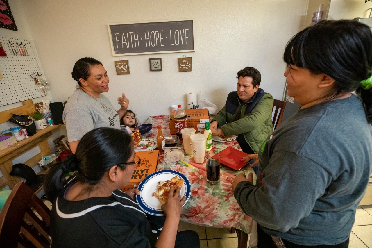 In their small apartment, the Aguilar family hosts Blanca (in black) for a dinner of Little Caesars pizza.