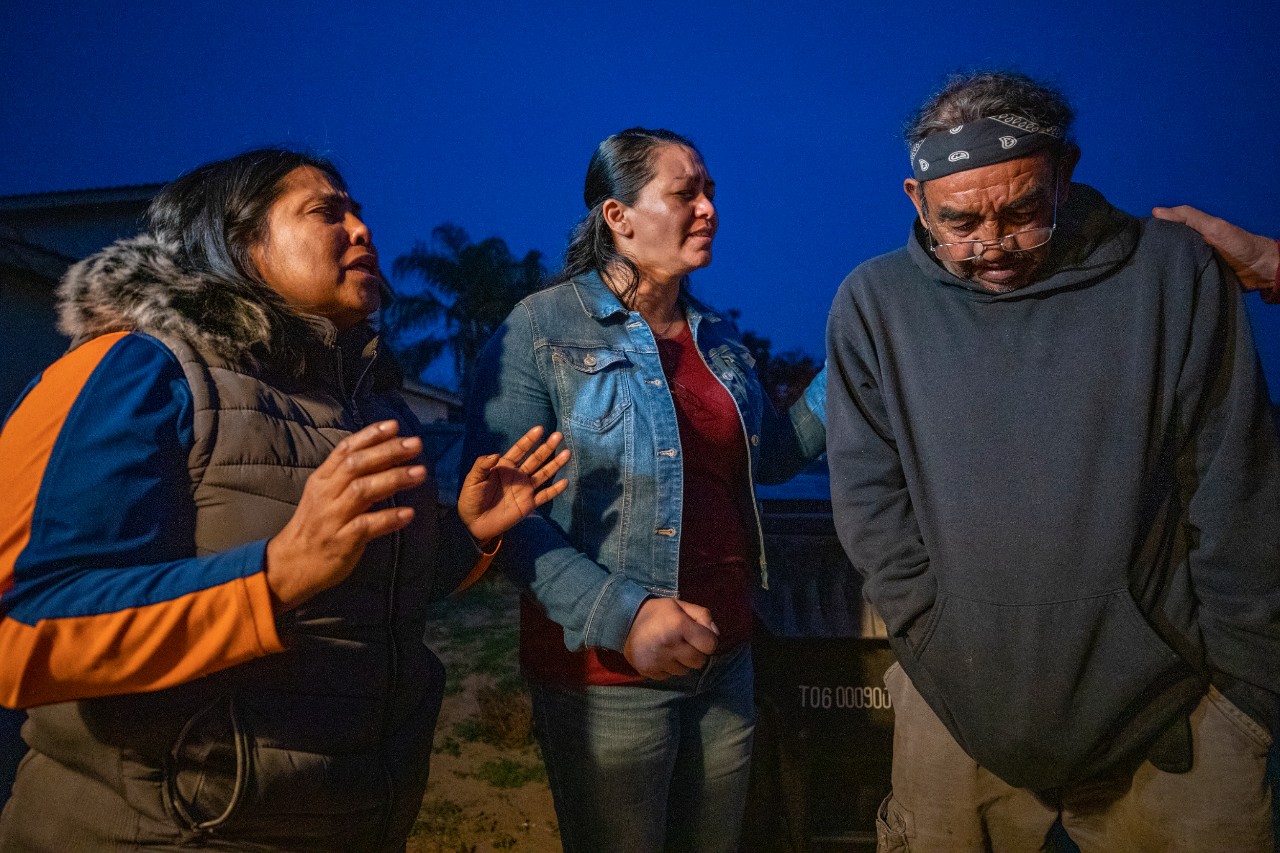 Blanca (left) and Rossana ask God to help 72-year-old farm worker Jose Luis fulfill his promise to his dying wife to take her ashes back to El Salvador for burial.