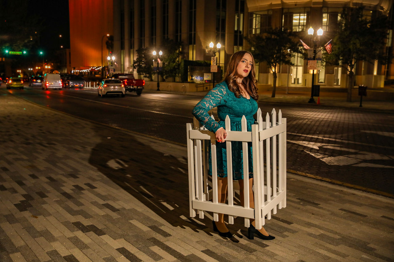 woman carrying white picket fence at night