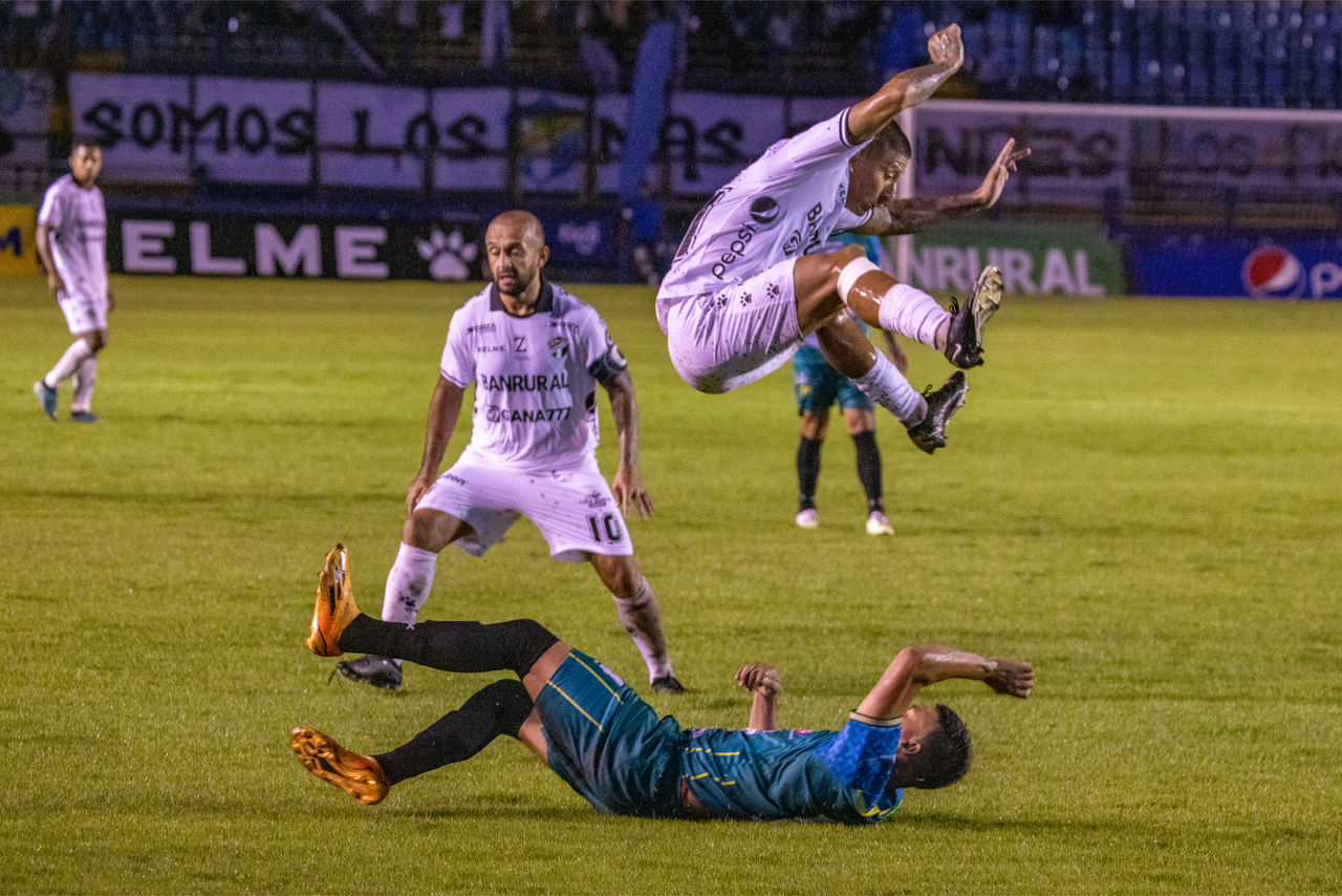 A Comunicaciones player tries to avoid a fallen Xinabajul player during their match.