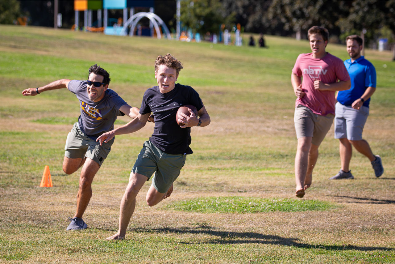 four male college students play flag football