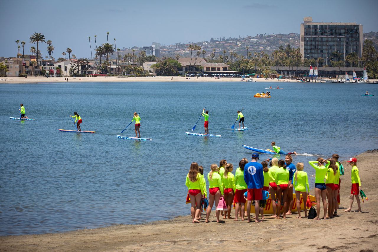 A group of junior lifeguards practice paddle boarding at Mission Bay Beach.