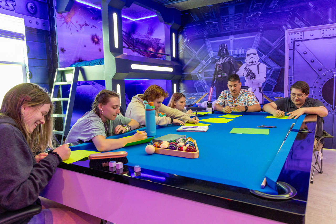 students work around a pool table in a Star Wars themed room