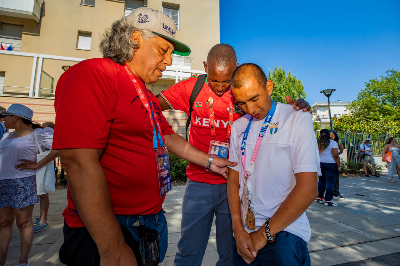 Cristobal L and David Cheromei pray with Guatemalan marathon runner