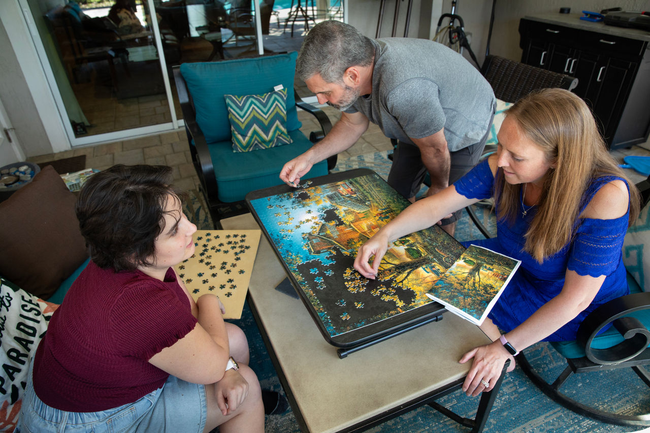 Jennifer Vanover, attorney with FLAG ministry. Jen, Mike and Hannah working on puzzles on their porch. 